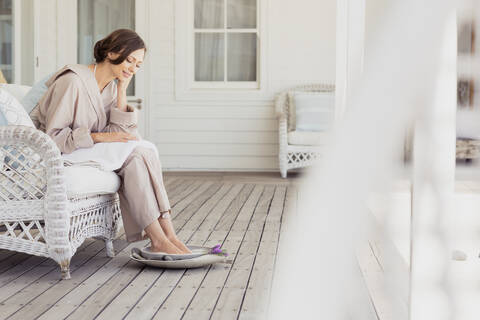 Frau nimmt ein Fußbad auf einer Veranda, lizenzfreies Stockfoto
