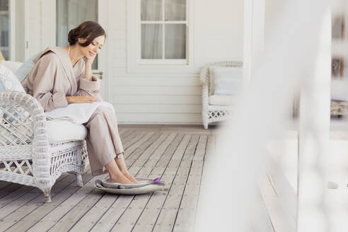 Frau nimmt ein Fußbad auf einer Veranda - SDAHF00524