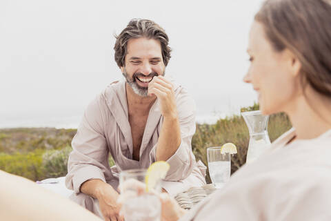 Glückliches, entspanntes Paar mit Getränken auf der Terrasse, lizenzfreies Stockfoto