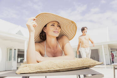 Frau entspannt auf Sonnenliege mit Mann im Hintergrund - SDAHF00542