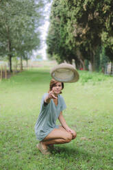 Young woman on a meadow throwing a hat - GIOF07997