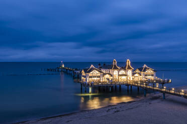 Germany, Mecklenburg-West Pomerania, Ruegen Island, Sellin, Illuminated pier on sea at dusk - WDF05785