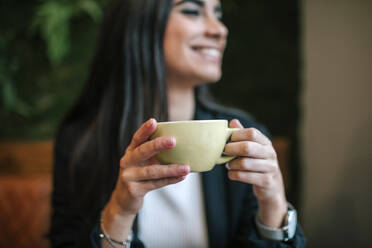 Crop-Ansicht einer glücklichen Frau in einem Café, die eine Tasse hält - GRCF00164