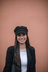 Porträt einer glücklichen Frau mit schwarzem Blazer und Mütze - GRCF00168