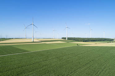 Deutschland, Bayern, Drohne Blick auf grüne Landschaft Felder im Sommer mit Windpark im Hintergrund - RUEF02614