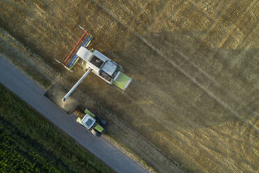 Germany, Bavaria, Drone view of combine harvester unloading grain on tractor - RUEF02631