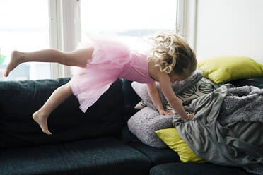 Mädchen in rosa Tutu-Kleid springt auf Sofa - JOHF09077