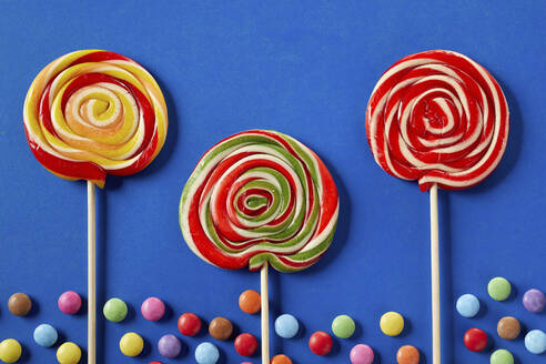 Chocolate drops and spiral lollipops on blue background - DREF00051