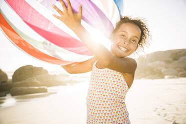 Happy girl holding inflatable ball on the beach - SDAHF00590