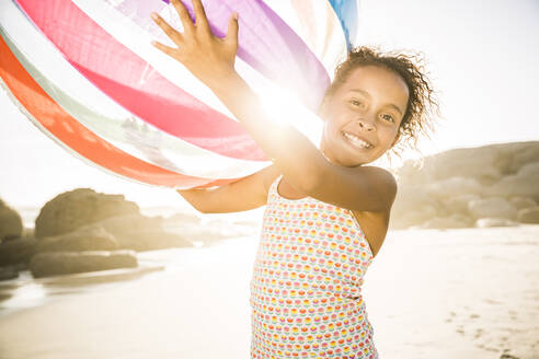 Glückliches Mädchen hält aufblasbaren Ball am Strand - SDAHF00590