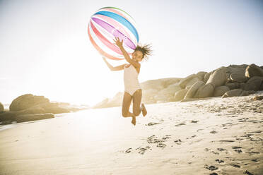 Glückliches Mädchen spielt mit aufblasbarem Ball am Strand - SDAHF00591