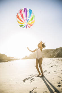 Glückliches Mädchen spielt mit aufblasbarem Ball am Strand - SDAHF00592