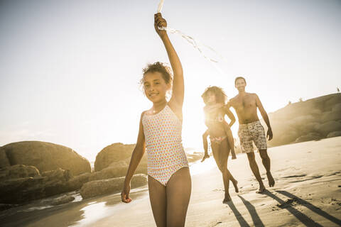 Happy girl with her family walking on the beach holding balloon string stock photo