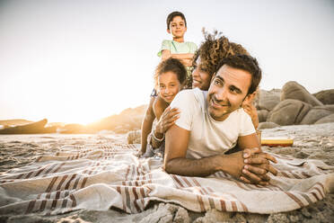 Eine glückliche Familie, die sich bei Sonnenuntergang am Strand vergnügt - SDAHF00619