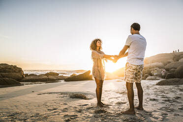 Happy couple holding hands on the beach at sunset - SDAHF00622