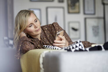 Blond woman using cell phone at home - RBF07049