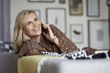 Smiling blond woman talking on the phone at home - RBF07050