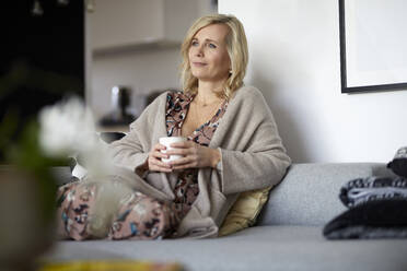 Blond woman relaxing at home sitting on couch - RBF07051