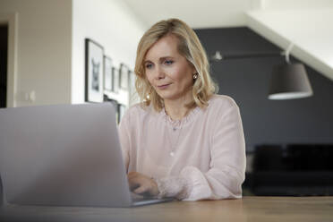 Blond woman using laptop at home - RBF07061