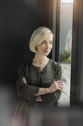 Portrait of content businesswoman looking out of window stock photo