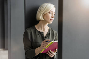 Porträt einer nachdenklichen Geschäftsfrau mit Notizbüchern, die in die Ferne schaut - BMOF00173