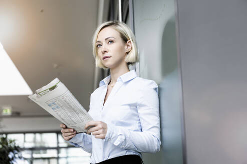 Porträt einer blonden Geschäftsfrau mit Zeitung - BMOF00182