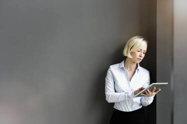 Portrait of blond businesswoman using digital tablet - BMOF00184