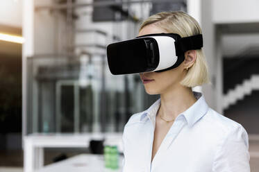 Woman wearing VR glasses in office - BMOF00185