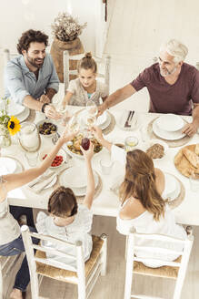 Familie beim gemeinsamen Mittagessen und Anstoßen mit Weingläsern - SDAHF00638