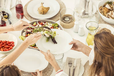 Close-up of family and friends having lunch together serving salad - SDAHF00641