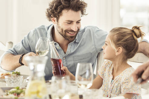 Vater und Tochter sitzen am Esstisch und stoßen an - SDAHF00642