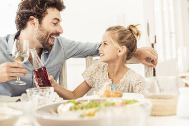 Father and daughter sitting at dining table toasting - SDAHF00661