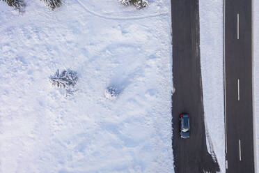 Deutschland, Bayern, Luftaufnahme eines Autos auf einer Landstraße im Winter - MMAF01265