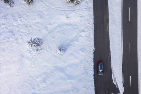 Deutschland, Bayern, Luftaufnahme eines Autos auf einer Landstraße im Winter - MMAF01265