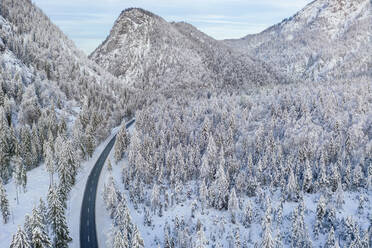 Germany, Bavaria, Aerial view of mountain highway and snow-covered forest in winter - MMAF01266