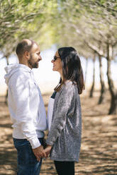 Couple holding hands in a park, face to face - DGOF00441