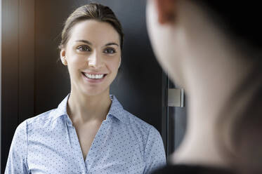 Porträt einer lächelnden Geschäftsfrau, die einen Kollegen im Büro trifft - BMOF00188