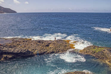 Spanien, La Gomera, Hermigua, Mann steht auf Klippe bei Meerwasserbecken - MAMF01152