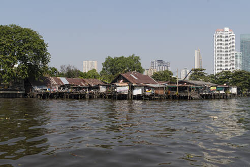 Hütten am Fluss Chao Phraya, Hochhäuser im Hintergrund, Bangkok, Thailand - CHPF00639