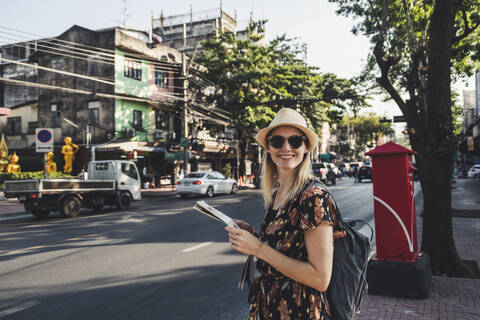 Lächelnde Frau mit Landkarte auf einer Straße, Bangkok, Thailand, lizenzfreies Stockfoto