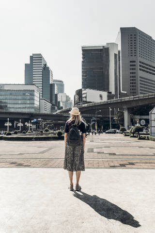 Rückansicht einer Frau mit Blick auf Hochhäuser, Bangkok, Thailand, lizenzfreies Stockfoto