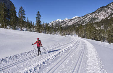 Ältere Frau beim Skilanglauf mit Karwendalgebirge im Hintergrund, Bayern, Deutschland - MRF02357