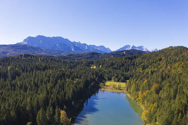Germany, Bavaria, Krun, Drone view of forest surrounding Grubsee lake with Wetterstein Mountains in background - SIEF09546