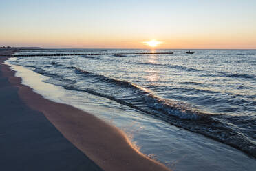 Deutschland, Mecklenburg-Vorpommern, Vitte, Sandstrand bei Sonnenuntergang mit Silhouette eines Fischerbootes im Hintergrund - WDF05819