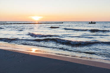 Deutschland, Mecklenburg-Vorpommern, Vitte, Sandstrand bei Sonnenuntergang mit Silhouette eines Fischerbootes im Hintergrund - WDF05820