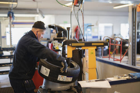 Mann wechselt Reifen in Garage - JOHF09107