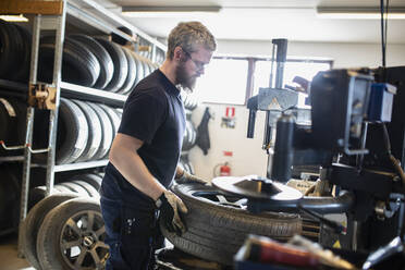 Man balancing the wheel in garage - JOHF09109