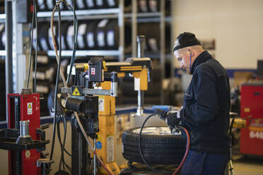 Mechaniker in der Werkstatt prüft Reifen - JOHF09113