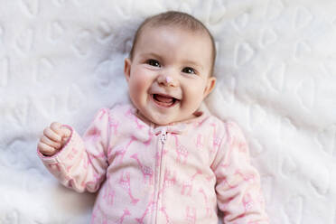 Portrait of laughing baby girl with pink heart-shaped candy on nose - GEMF03430