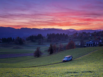 Slovenia, Sveti Tomaz, Car driving along countryside dirt road at moody dusk - HAMF00581